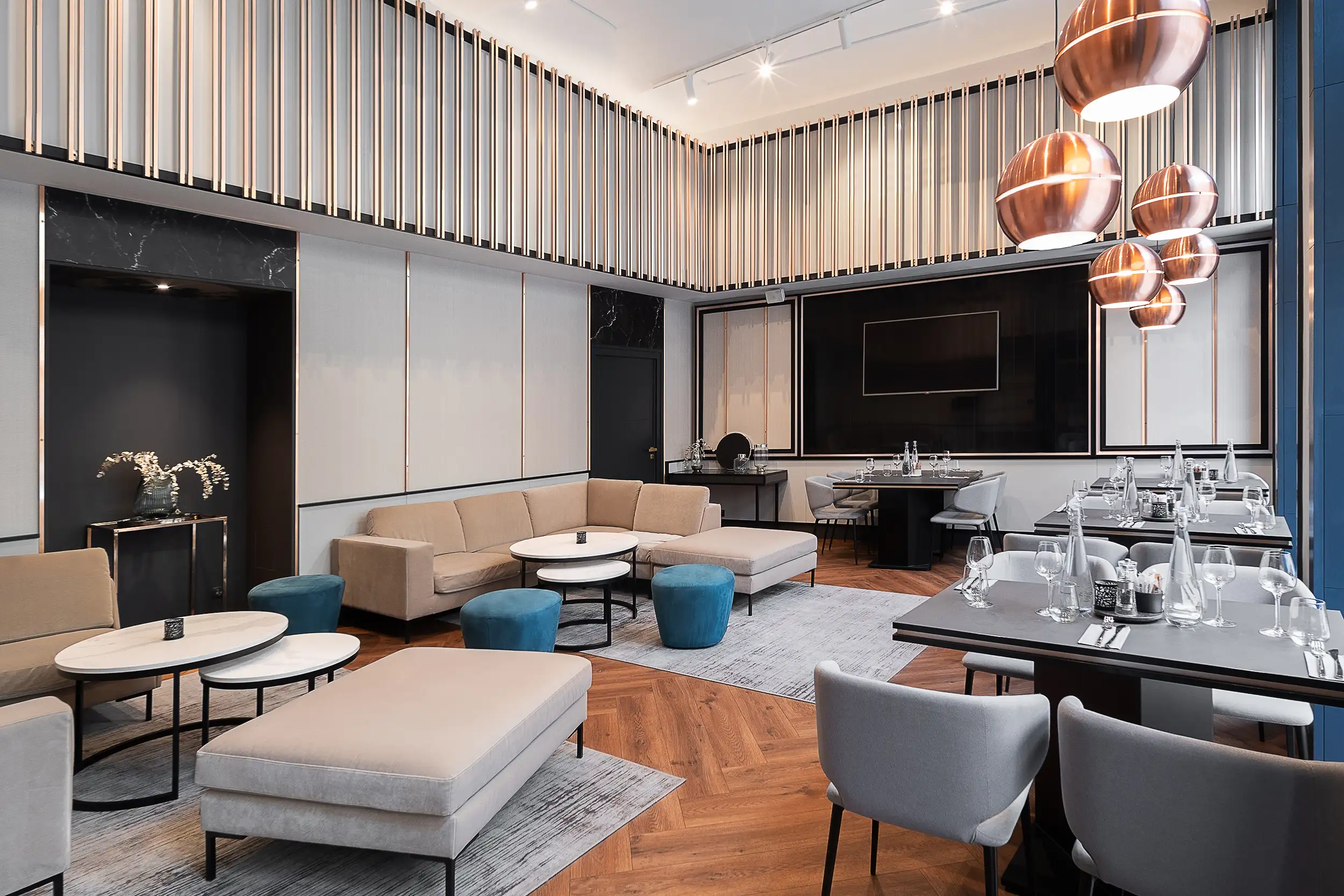 modernes restaurant mit integrierter lounge und chill out bereich, gepolsterten sofas, runden couchtischen und kupferfarbenen pendelleuchten