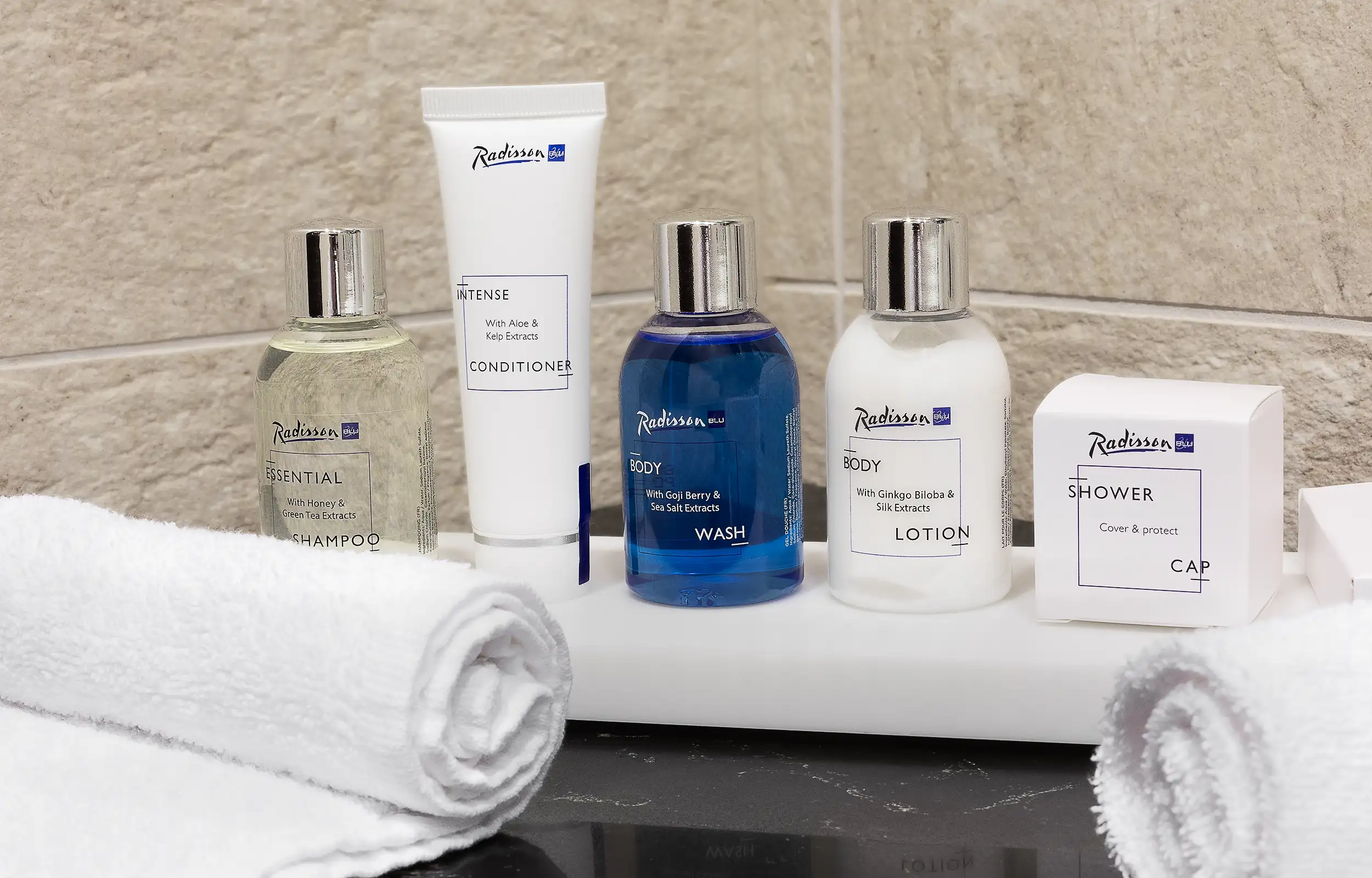 Detailaufnahme der Badezimmerausstattung im Radisson Blu: Shampoo, Conditioner, Duschgel, Lotion und Duschhaube
