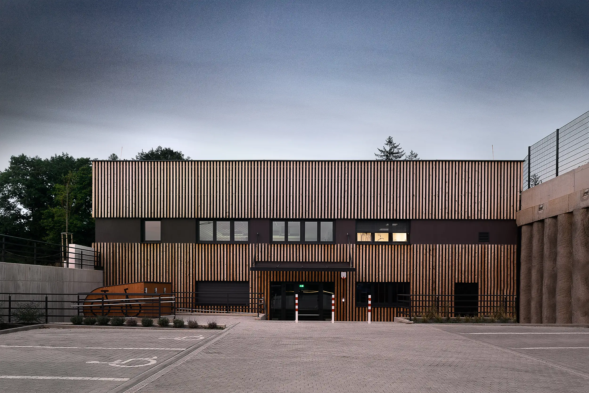 Front view of the modern sports hall in Světice near Prague with vertical wooden cladding captured during twilight by architectural photographer Ondrej Hromadko.
