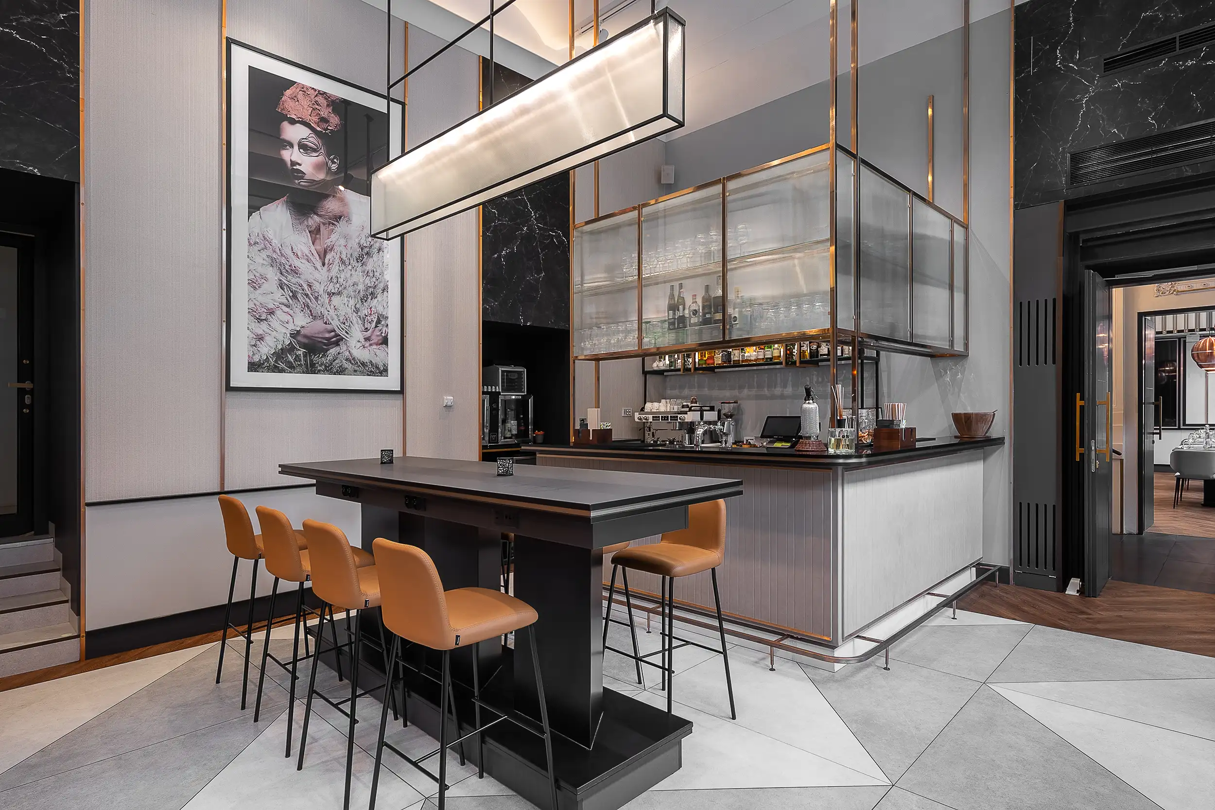 Elegantní hotelový bar, laděný v šedých tónech, doplněný o oranžové barové židle v Radisson Blu v Praze, České republice