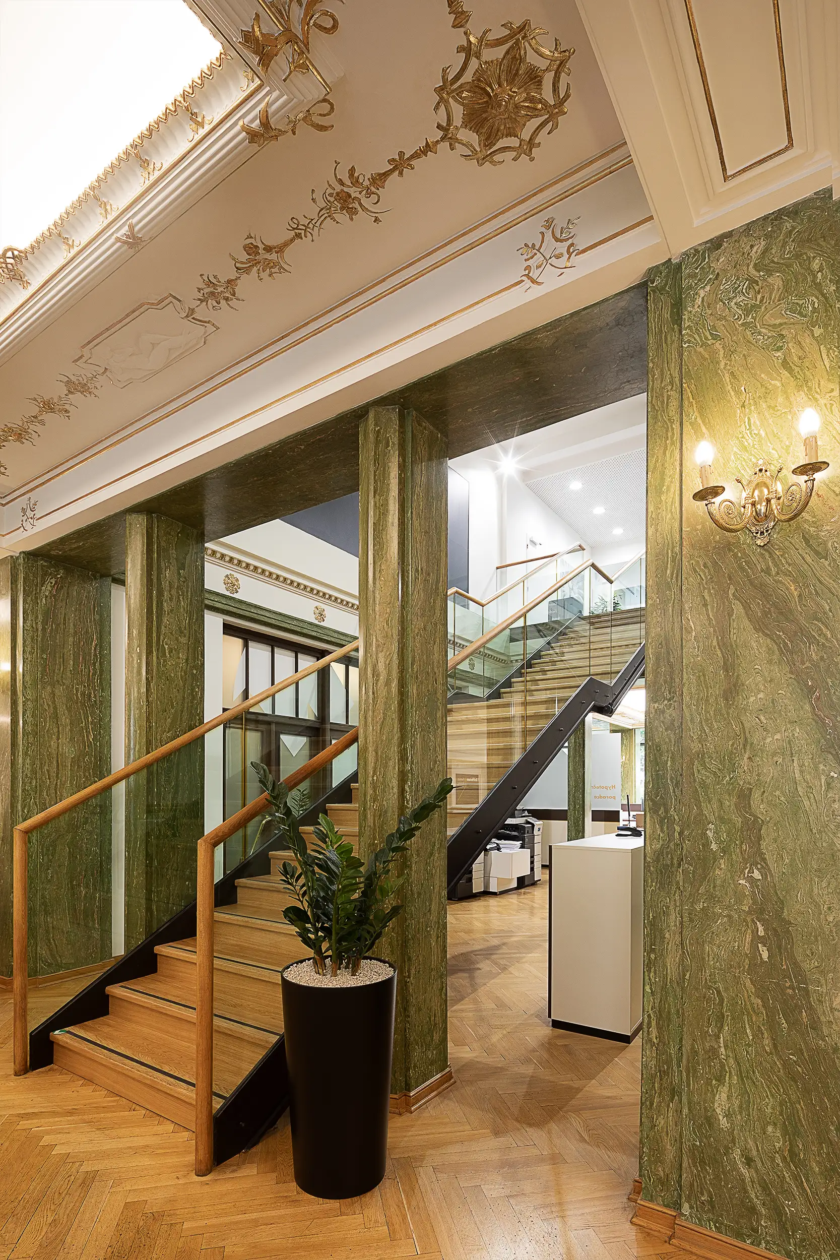 The stairs in a green-cream-toned secession interior of Raiffeisenbank at Palace Astra on Wenceslas Square in Prague, Czech Republic, captured from an angle to see both floor levels.