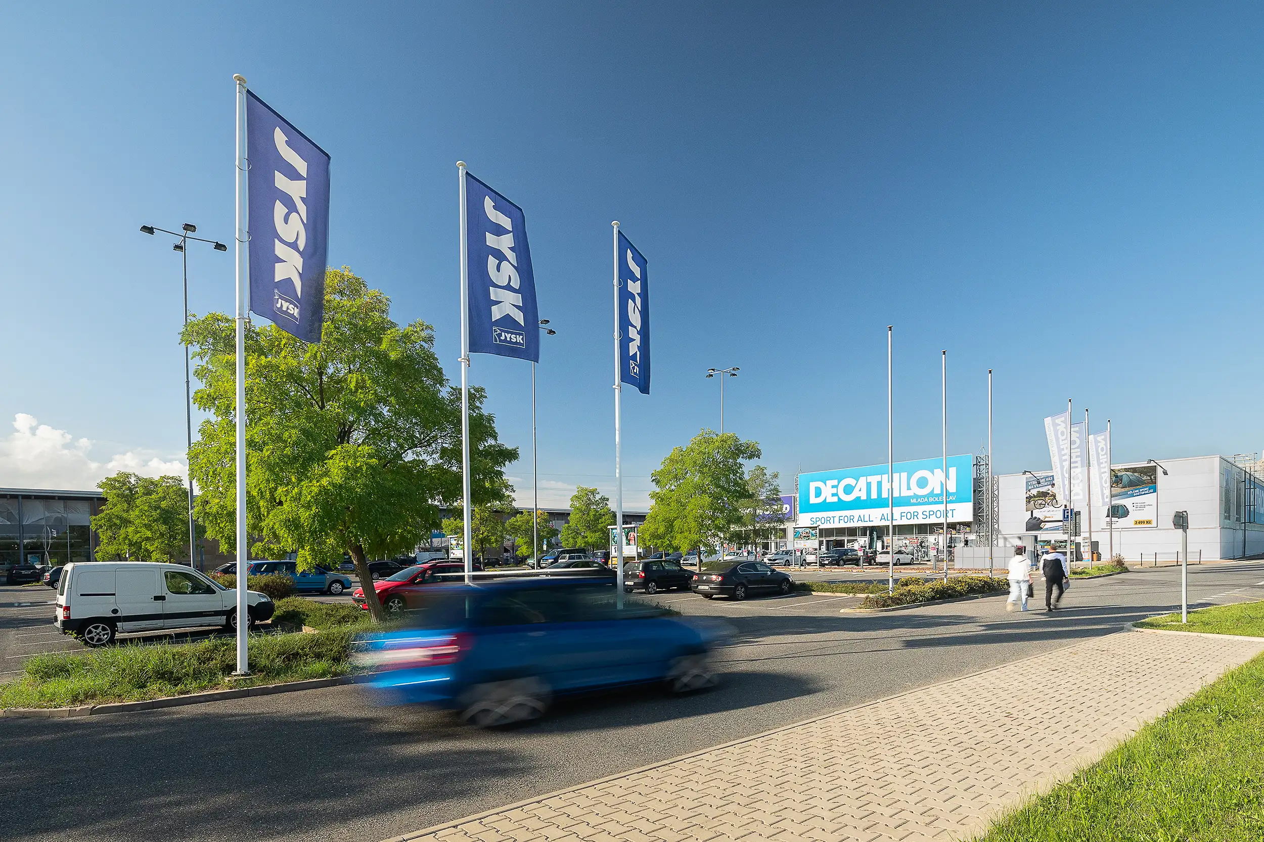 Hero photography of the Retail park in Mladá Boleslav contains an overview of the whole area with a car and people blurred in motion in the foreground.