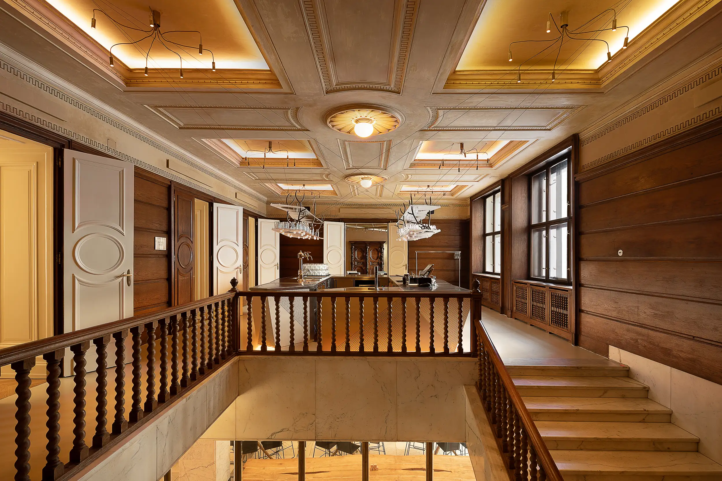 The wide-angle interior photograph showcases a central square with a bar between private lounges in the Červený Jelen restaurant in the Špork Palace in Prague, Czech Republic, in a combination of wood and stone decor.