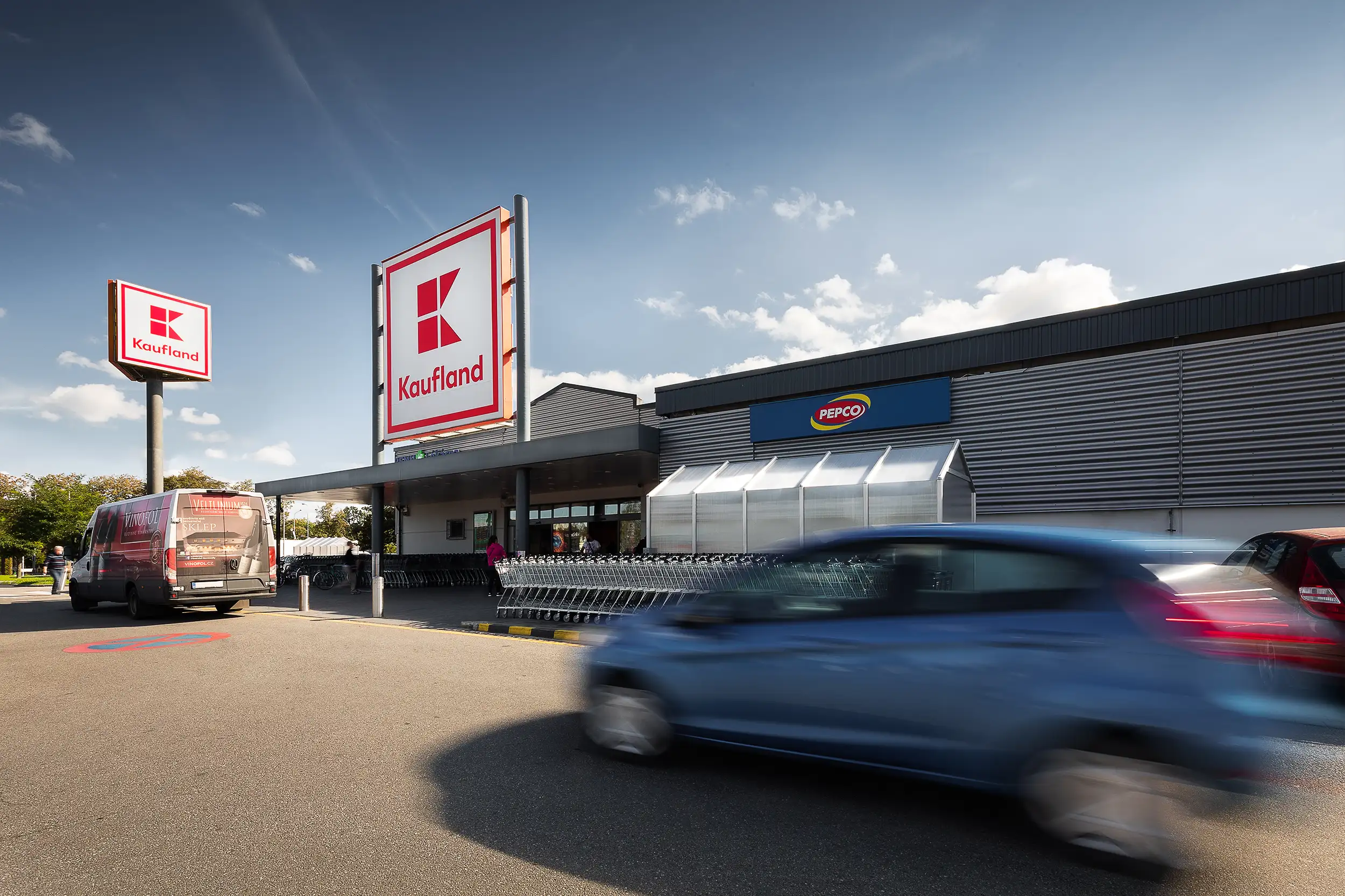 Hero shot of the Kaufland store in České Budějovice, Czech Republic, showing the building captured in the backlight, with a car blurred in motion in the foreground.