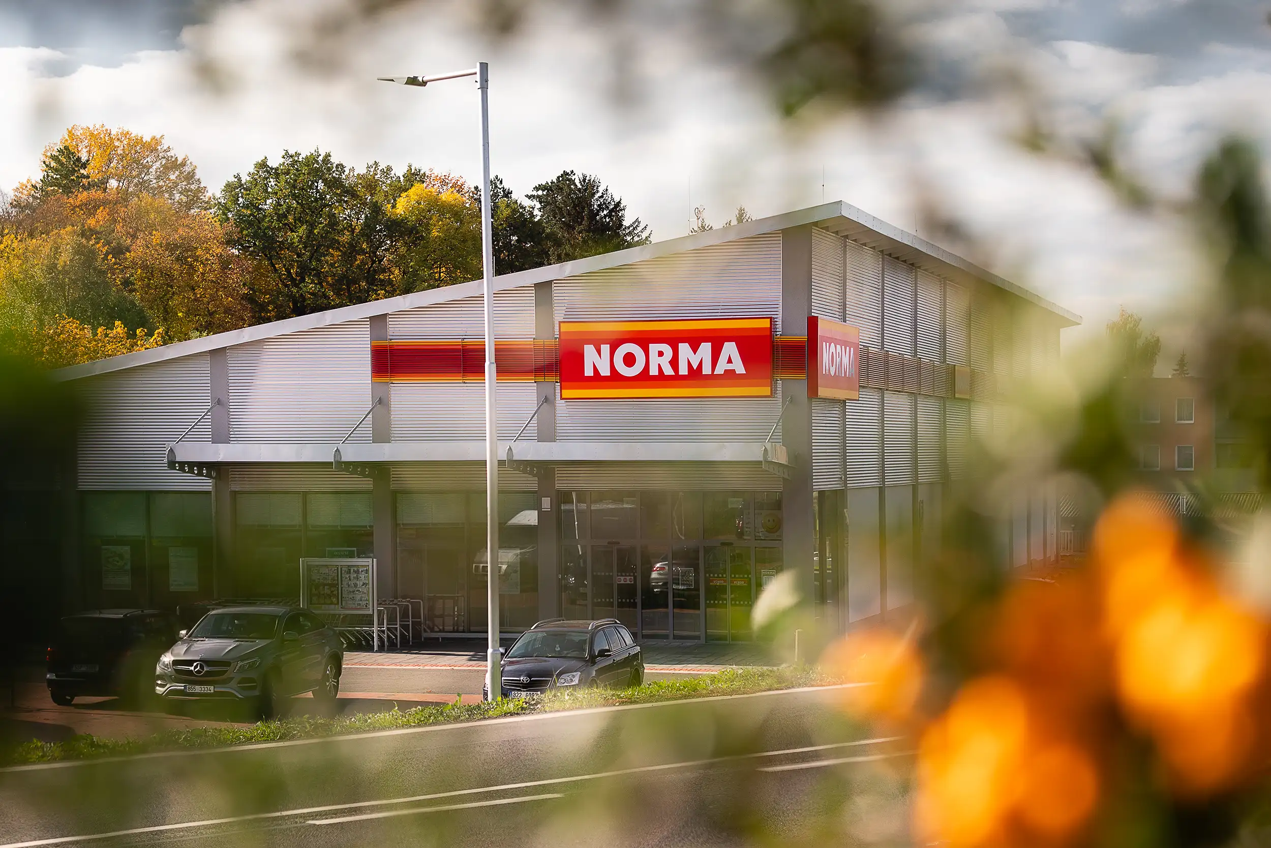 Image of Norma shopping store in Pobořany, Czech Republic, captured through the blurred greenery.