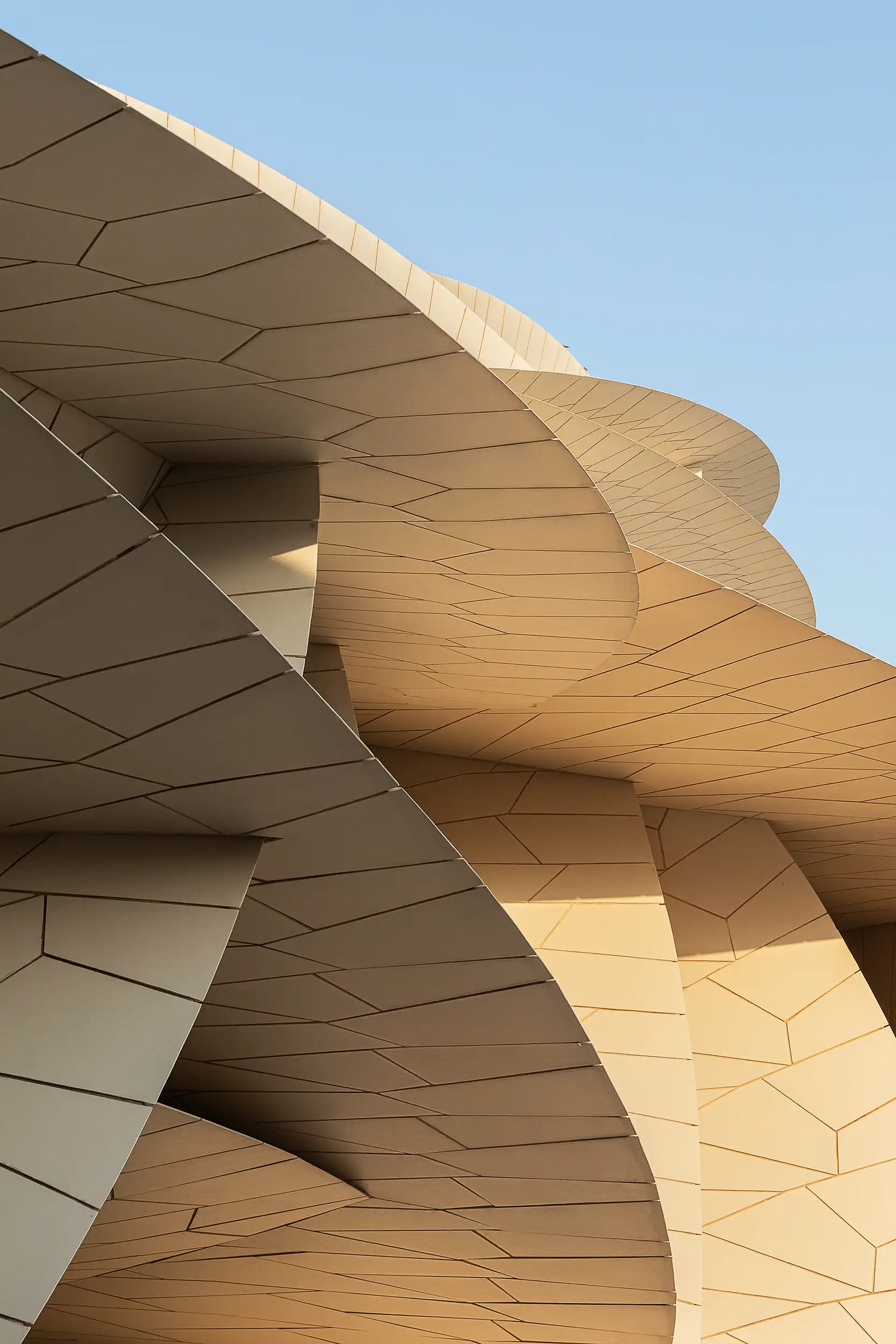 A detailed abstract photograph showcases the structures of the modern Qatar National Museum building in Doha captured in daylight.