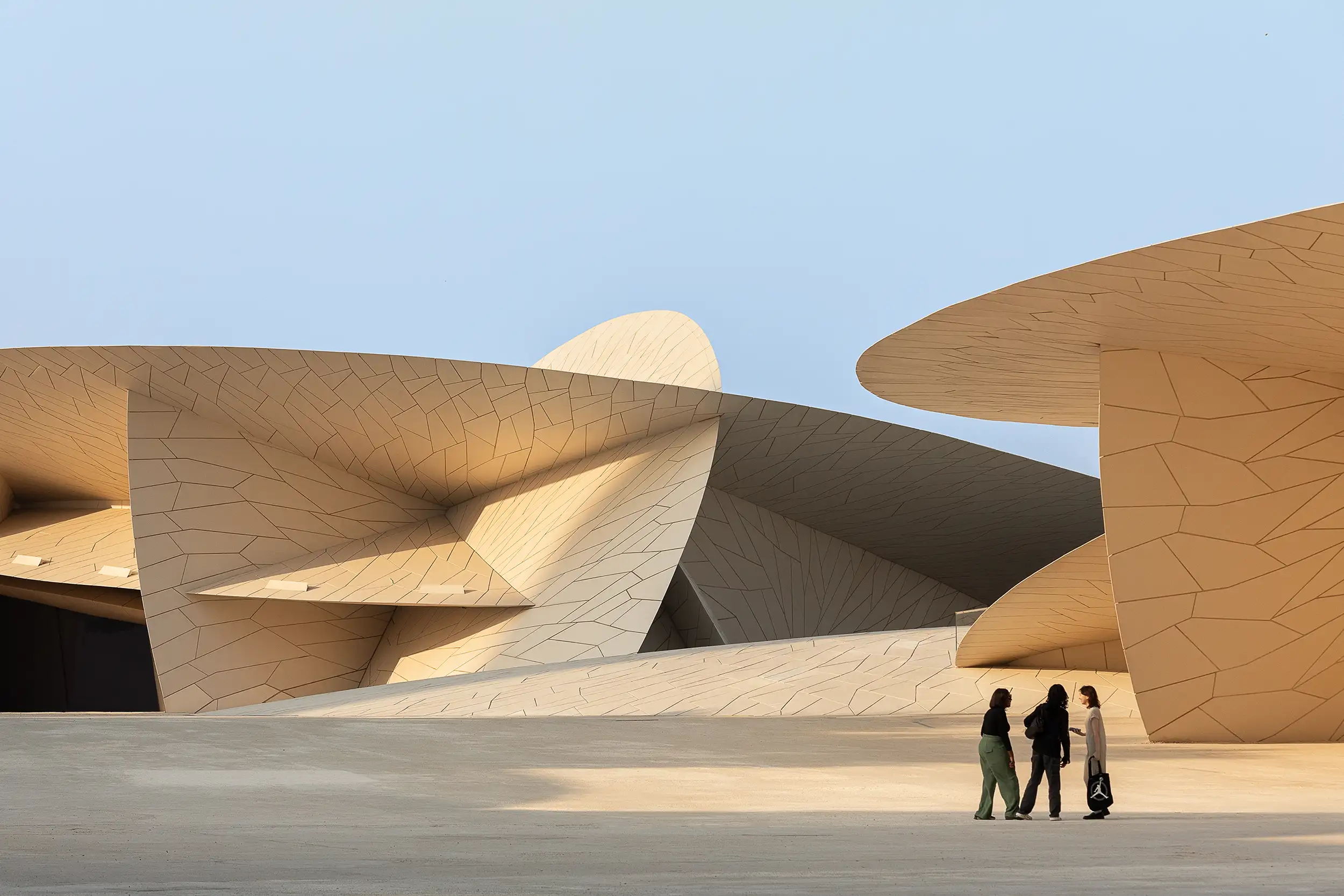 Three women are standing before the large structural discs of modern architecture.