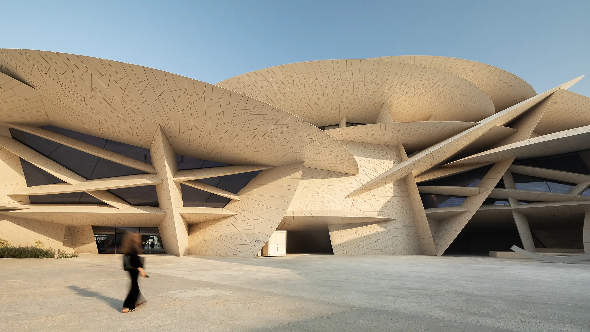 A woman blurred by motion walks before the futuristic modern architecture in Doha.