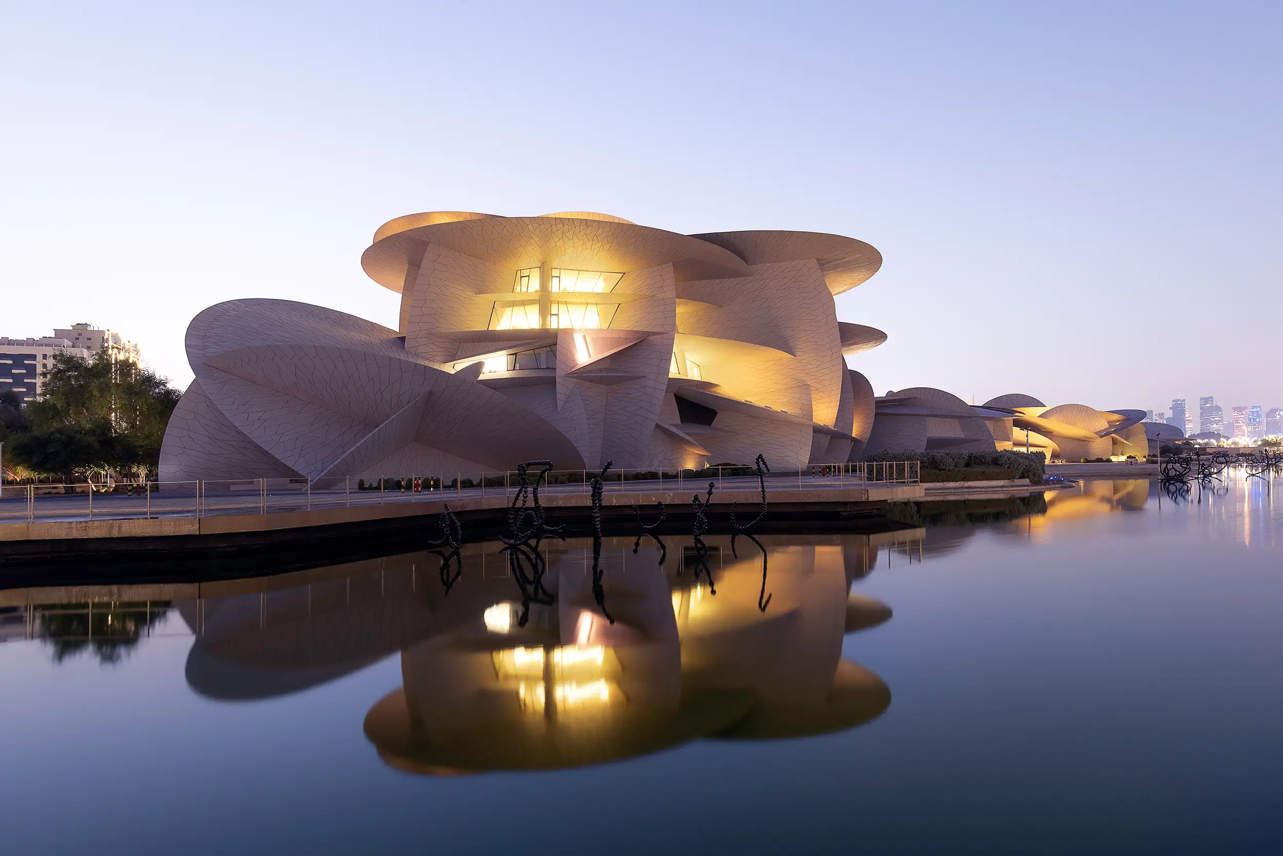 An enlightened modern architectural structure of the National Museum, captured over the water surface with a reflection during dusk.