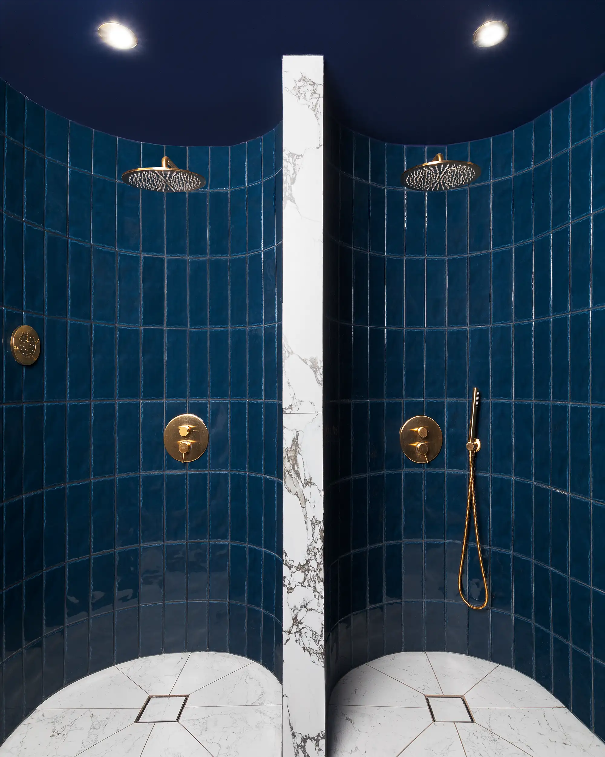 Vertical photo of the isolated showers in the hotel wellness centre, coated with dark blue tiles.