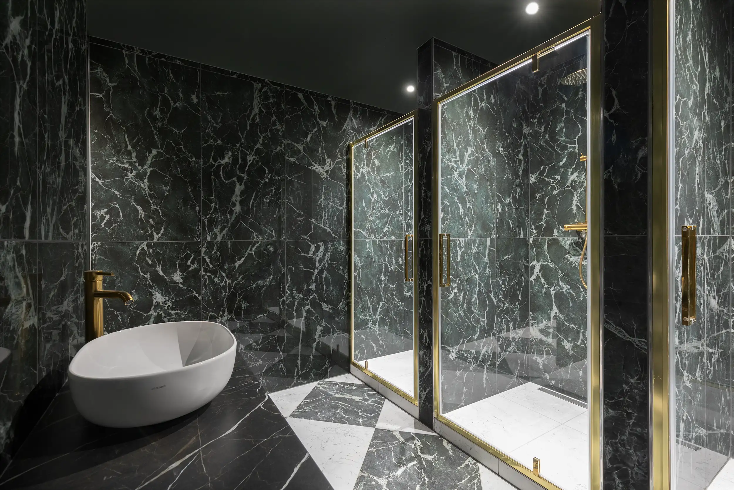 The men's locker room in the hotel's wellness center, lined with luxurious black marble, equipped with three golden shower corners.