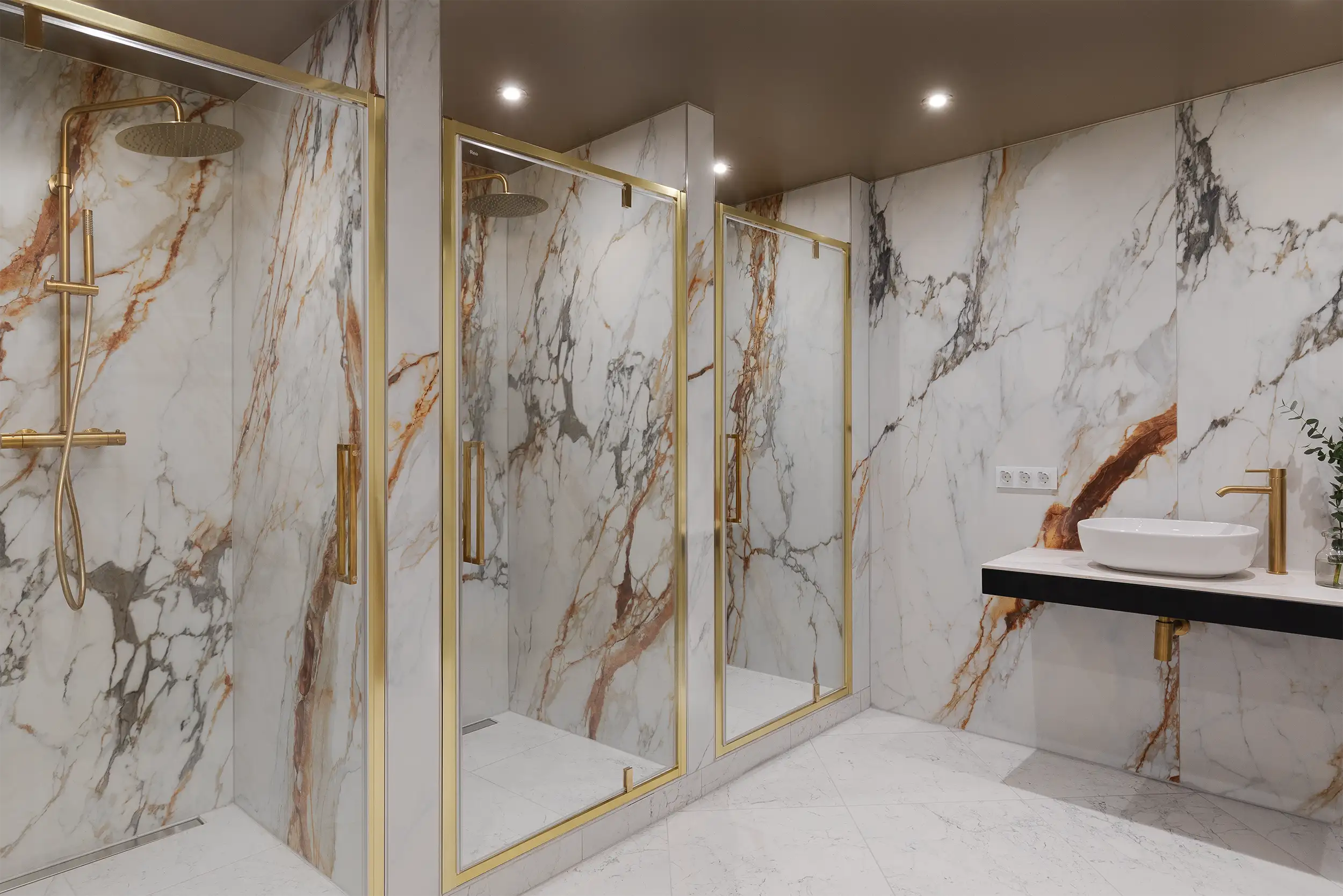 The ladies's locker room in the hotel's wellness center, lined with luxurious white marble, equipped with three golden shower corners.