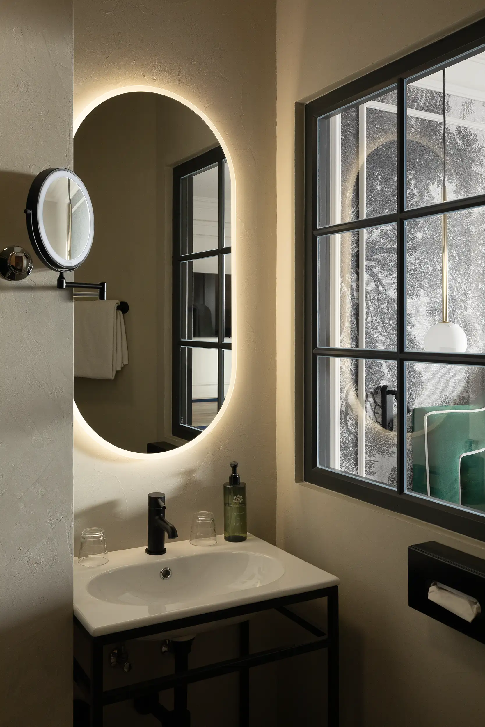 Minimalistic hotel bathroom lit by sun coming through the window shared with the bed room.