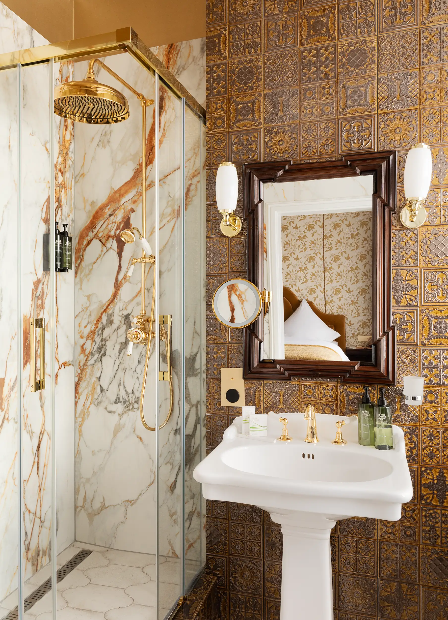 Luxury hotel bathroom toned in beige-golden colors equipped with a shower with a monolithic marble block and decorative tiling in oriental style.
