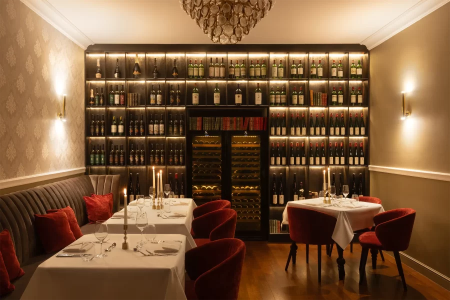 Restaurantbereich im Schlosshotel Althörnitz mit wandhoher Weinregalwand und gedeckten Tischen.