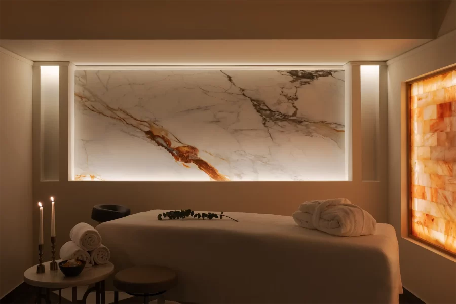 Wellness-Massageraum eines Hotels mit Liege, indirekter Beleuchtung und zurückhaltender, dunkler Farbgestaltung.