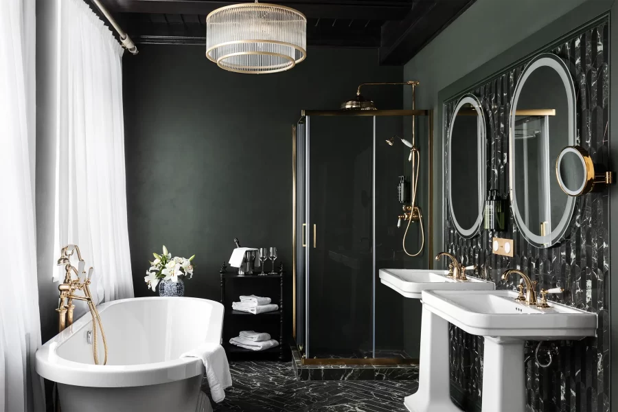 Luxuriöses und geräumiges Schlosshotel-Badezimmer in Dunkelgrün mit freistehender Badewanne, Dusche und zwei Waschbecken.